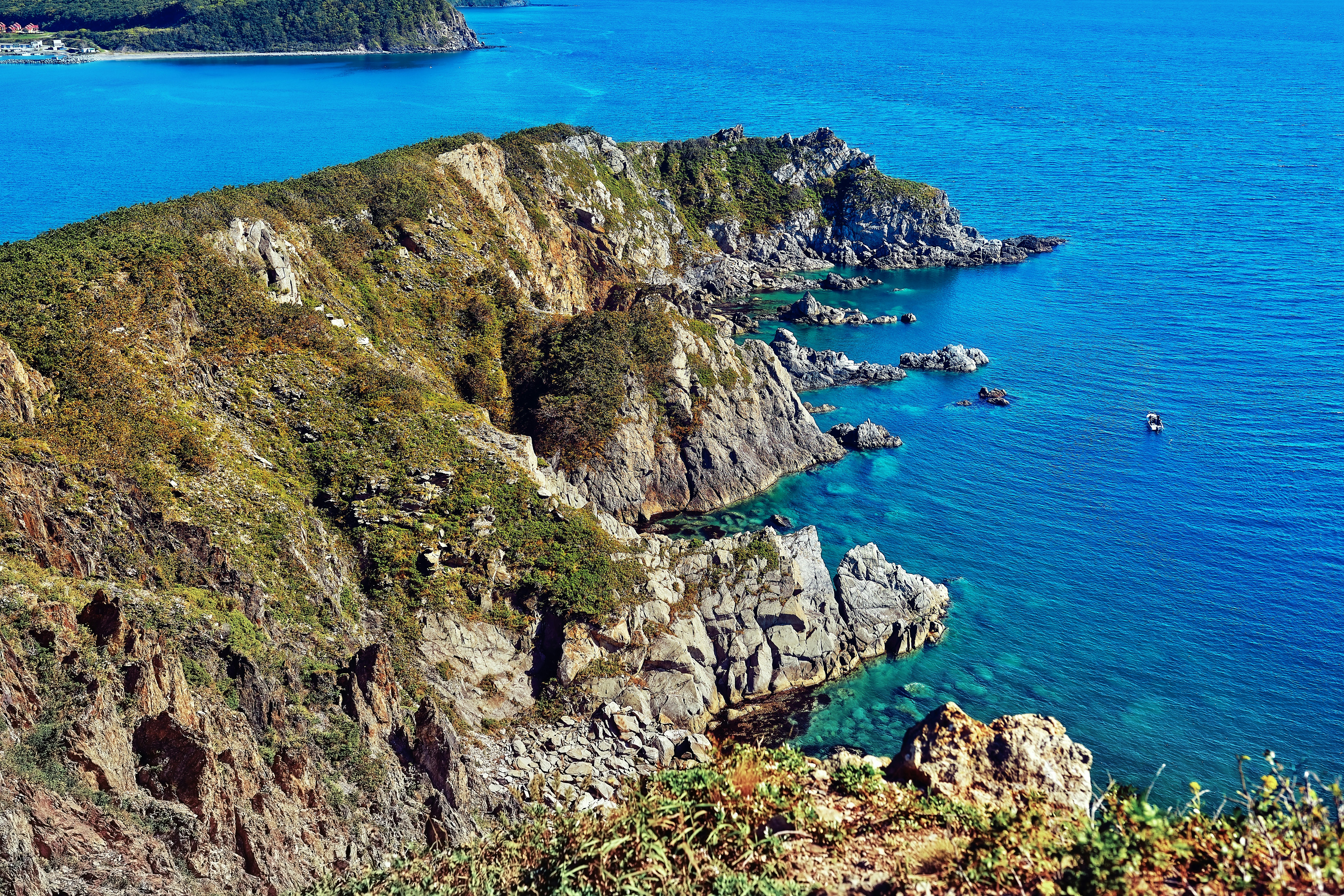 green and brown rock formation beside blue sea during daytime